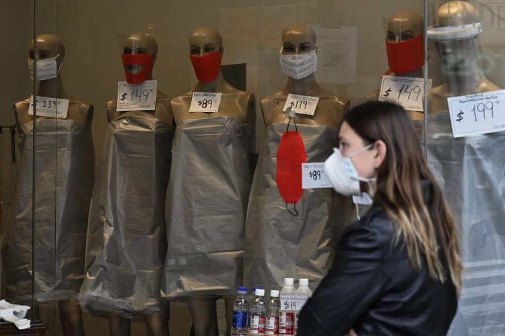 A woman looks at mannequins displaying face masks on the window of a store -since it is forbidden to sell clothing during the lockdown imposed by the government against the spread of the new coronavirus- in Buenos Aires, Argentina, on May 22, 2020. - Argentina is expected to pass the 10,000 infections of COVID-19 since the first positive case on March 3. (Photo by JUAN MABROMATA / AFP)