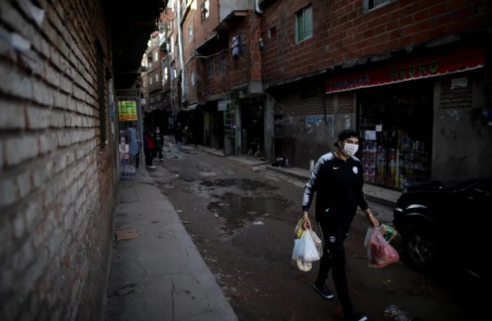 A man walks on a street after shopping during a government-ordered lockdown to curb the spread of the new coronavirus at a slum in Buenos Aires, Argentina, Sunday, April 26, 2020. (AP Photo/Natacha Pisarenko)