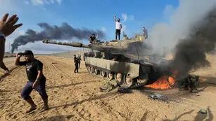 Palestinos celebran por un tanque israelí destruido en la valla de la Franja de Gaza al este del sur de Khan Younis (AP).
