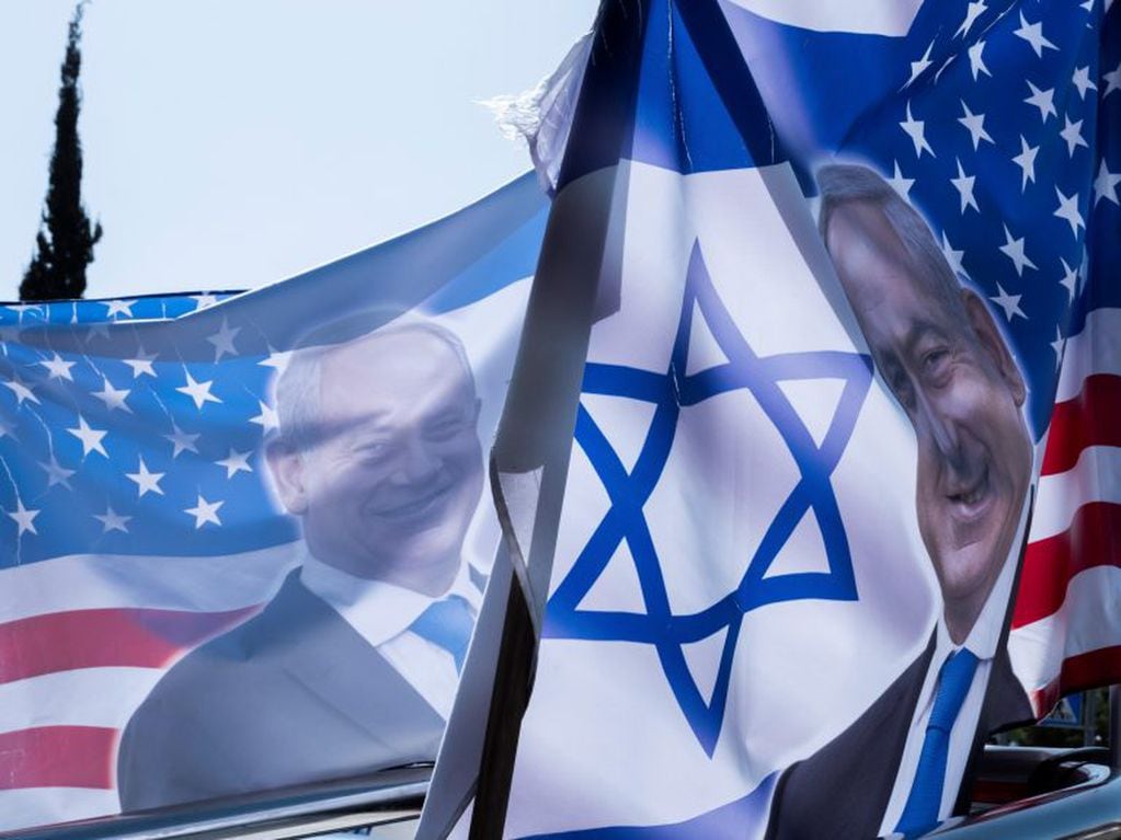 Un par de banderas con el retrato del primer ministro israelí, Benjamin Netanyahu, junto a la Estrella de David y las barras y estrellas