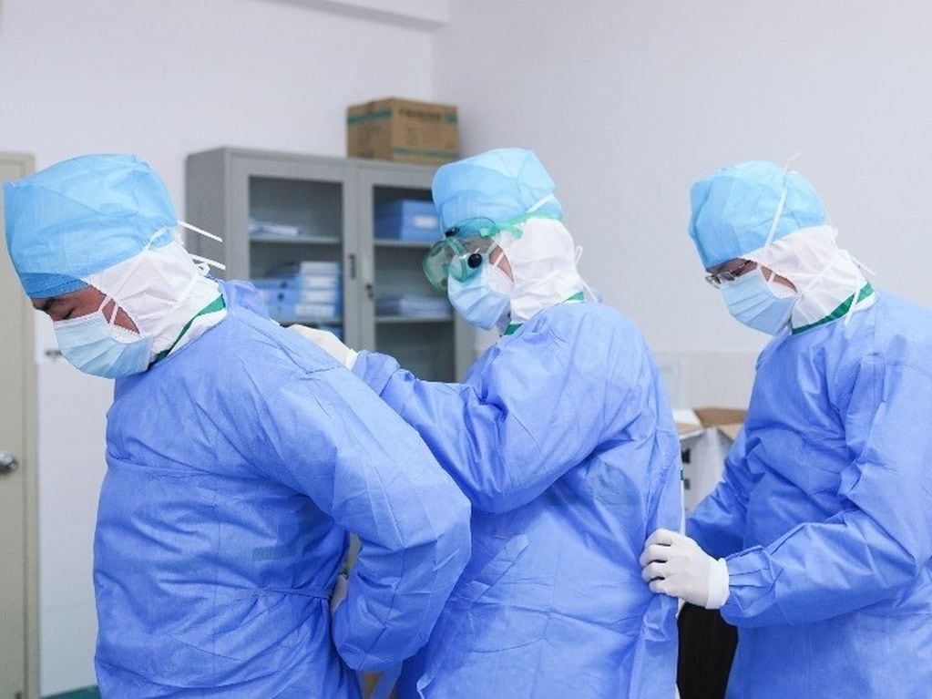 Trabajadores médicos se ayudan mutuamente para ponerse trajes protectores contra el coronavirus (Imagen ilustrativa).