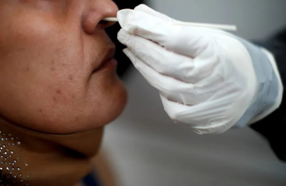 A healthcare worker conducts a nasal swab test for COVID-19 from inside a freestanding coronavirus testing isolation booth at a hospital in Buenos Aires, Argentina,  Monday, Oct. 19, 2020. (AP Photo/Natacha Pisarenko)HOSPITAL POSADAS - PROVINCIA DE BUENOS AIRES - HISOPADO HISOPADOS CASOS DEL DIA  TESTEO TESTEOS