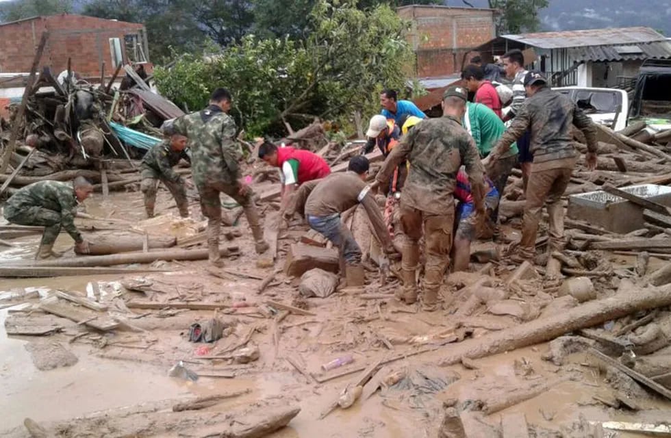 In this handout photo released by the Colombian National Army, soldiers and residents work together in rescue efforts in Mocoa, Colombia, Saturday, April 1, 2017, after an avalanche of water from an overflowing river swept through the city as people slept