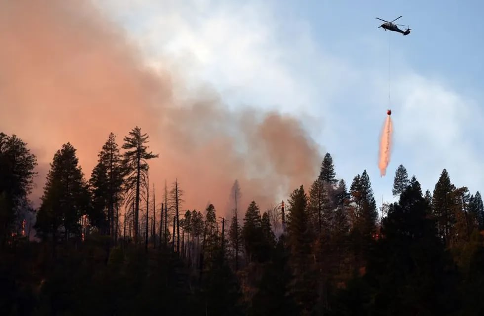 TOPSHOT - A helicopter drops water on a burning ridge in the Feather River Canyon, east of Paradise, California on November 11, 2018. - The number of dead in a wildfire raging in California rose to 29 on November 11, matching the deadliest in the state's history as recovery teams found six more bodies in the grim search through the wreckage. (Photo by Josh Edelson / AFP)