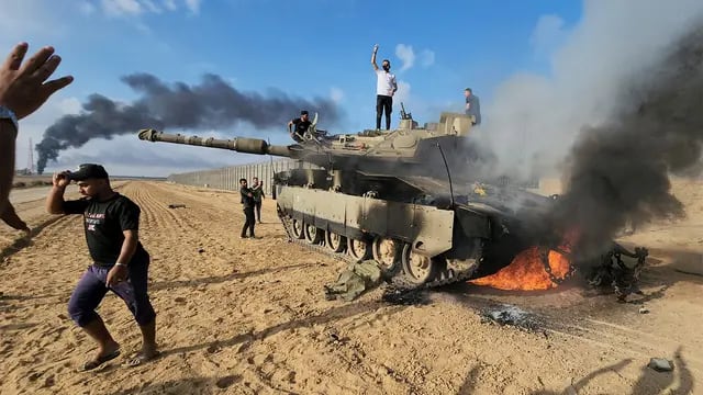 Palestinos celebran por un tanque israelí destruido en la valla de la Franja de Gaza al este del sur de Khan Younis (AP).