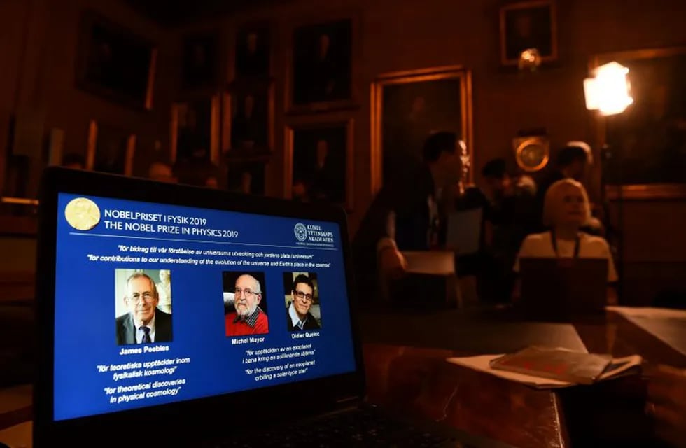 La computadora muestra a los tres ganadores del Premio Nobel: James Peebles, Michel Mayor y Didier Queloz. Foto: Jonathan NACKSTRAND/AFP.