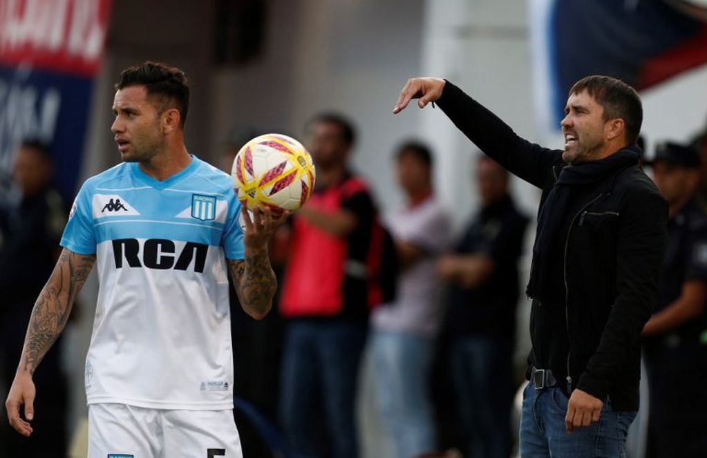 Racing Club's coach Eduardo Coudet, right, shouts instructions to his players as defender Eugenio Mena prepares to throw in the ball during an Argentine Superliga soccer match in Victoria, on the outskirts of Buenos Aires, Argentina, Sunday, Mar. 31, 2019. (AP Photo/Mariano Blanc)
