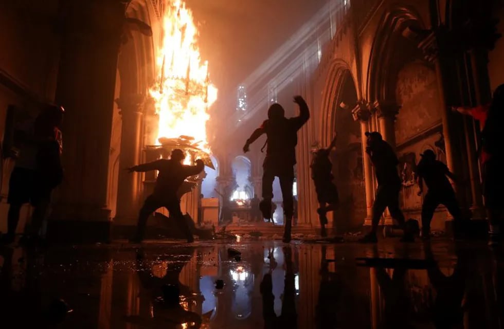 Protesters storm the San Francisco de Borja church, that belongs to Carabineros, Chile's national police force, on the one-year anniversary of the start of anti-government mass protests over inequality in Santiago, Chile, Sunday, Oct. 18, 2020.  (AP Photo/Esteban Felix)