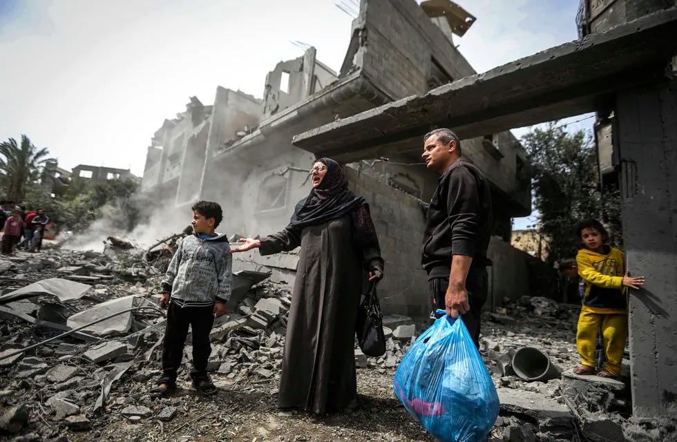 Palestinos recopilan sus pertenencias entre los escombros de un edificio residencial tras un ataque aéreo israelí en el campo de refugiados de Maghazi, en el centro de la Franja de Gaza, el 29 de marzo de 2024.
