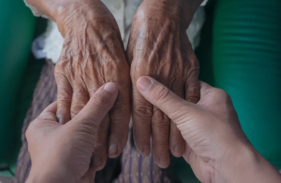 Mujer agarrando las manos de un anciano.