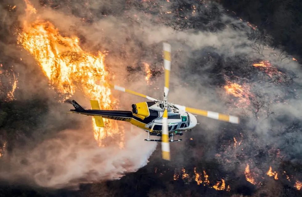 Un helicóptero de bomberos del Condado de Los Angeles sobrevuela un gran incendio en Bel Air, California (EE.UU.). (Foto: EFE/JOHN CETRINO)