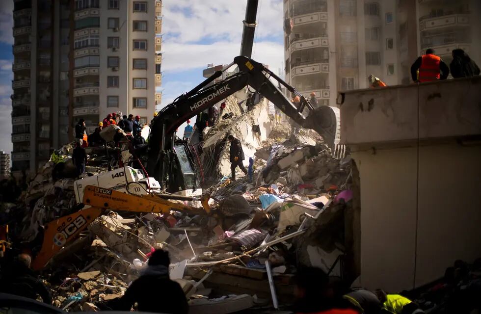 Miembros de rescate de emergencia buscan personas en un edificio destruido en Adana, Turquía.