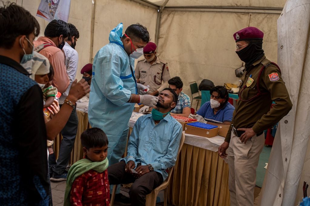 Un trabajador de la salud toma una muestra de hisopado nasal de un pasajero para realizar la prueba de coronavirus en una terminal de autobuses en Nueva Delhi, India. Foto: AP