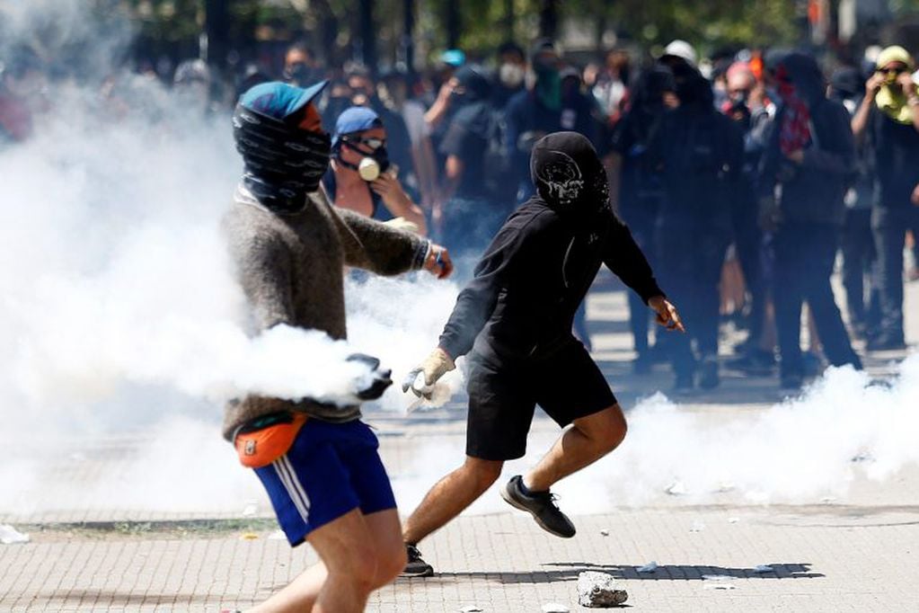 Un manifestante devuelve una bomba lacrimógena a personal de Carabineros durante una nueva jornada de protestas en Chile (Foto: EFE).