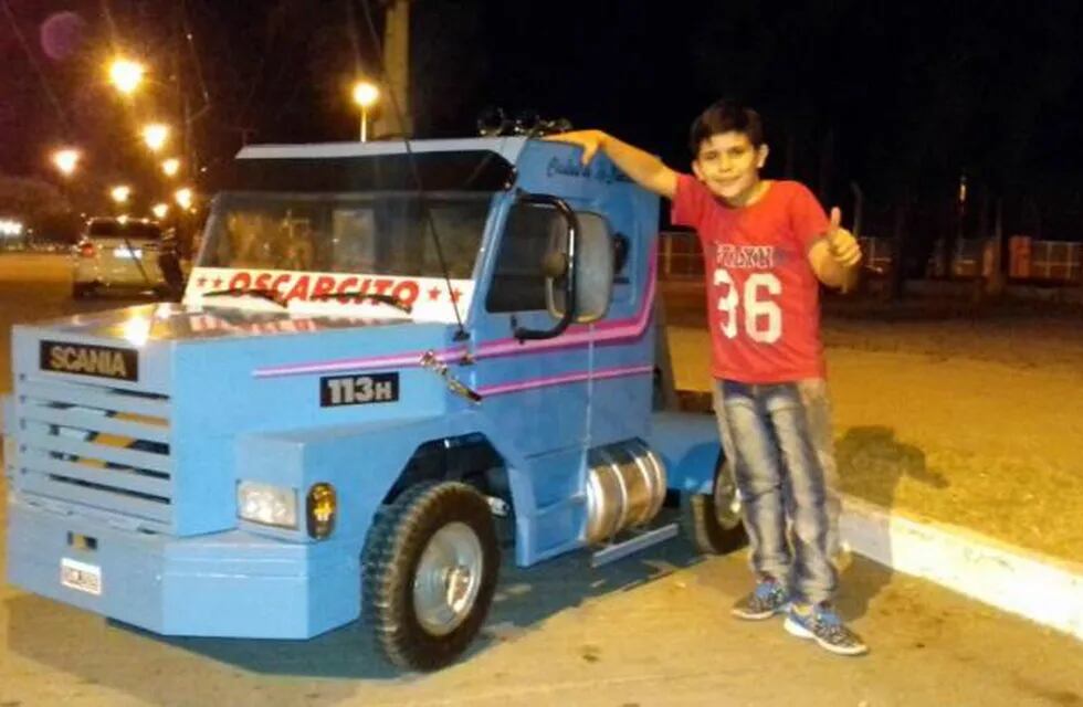El hijo de Oscar posa orgulloso con el camión a escala fabricado por su padre.