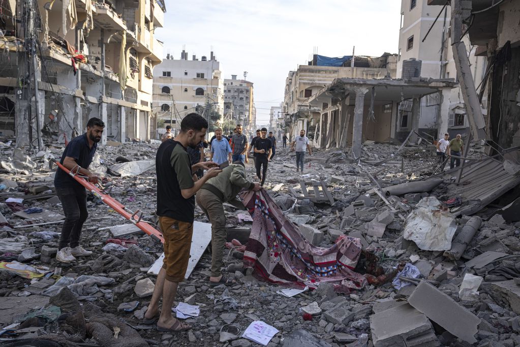 Varios palestinos recogen cadáveres de entre los escombros tras un bombardeo israelí, el miércoles 11 de octubre de 2023, en la Ciudad de Gaza. (AP Foto/Fatima Shbair)