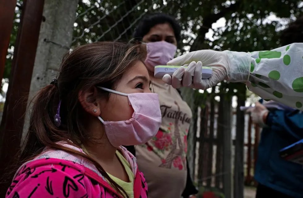 A girl from Altos de San Lorenzo neighbourhood, near the city of La Plata, 65 km from Buenos Aires, has her temperature taken by a health worker on May 24, 2020 amid the COVID-19 coronavirus pandemic. - While the number of COVID-19 cases in Argentina has raised to more than 11,000, the \