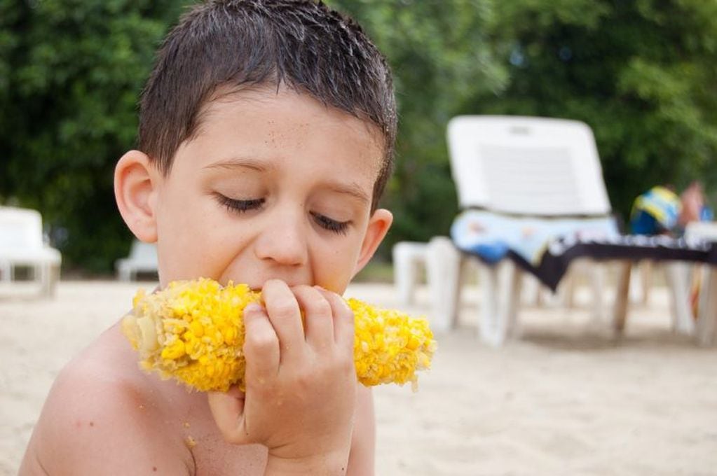 Niño comiendo choclo en la playa (PIXABAY)