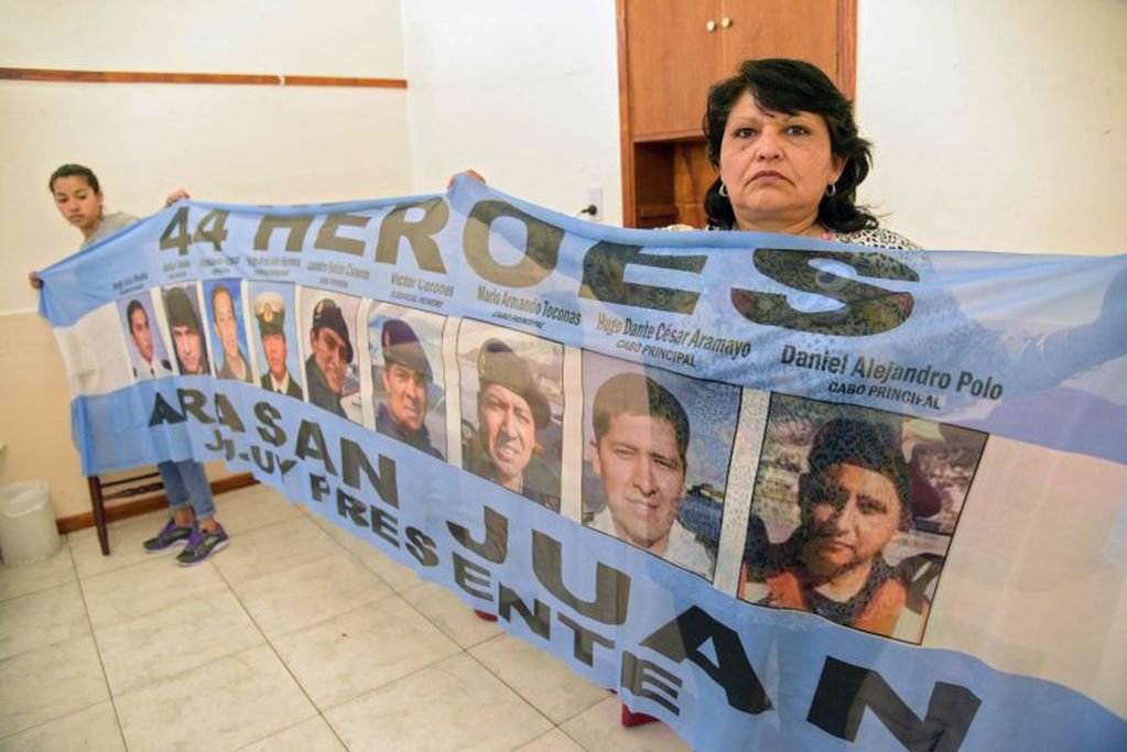 Yolanda Mendiona y Lourdes Melián, hermana del cabo primero David Melián, sostienen una bandera con los retratos de los nueve tripulantes jujeños del submarino San Juan. (Mara SOSTI / AFP)