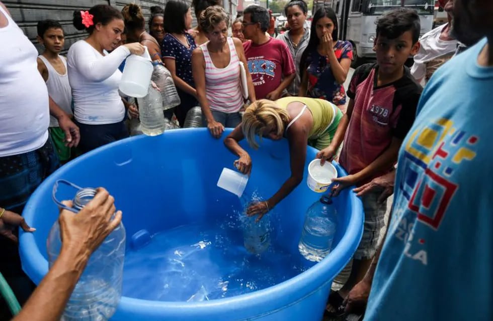 People fill cans with potable water in Caracas on March 10, 2019, during the third day of a massive power outage which has left Venezuelans without communications, electricity and water. - The unprecedented power outage already left 15 patients dead and threatens to extend indefinitely, increasing distress for the severe political and economic crisis hitting the oil-rich South American nation. (Photo by Cristian HERNANDEZ / AFP)