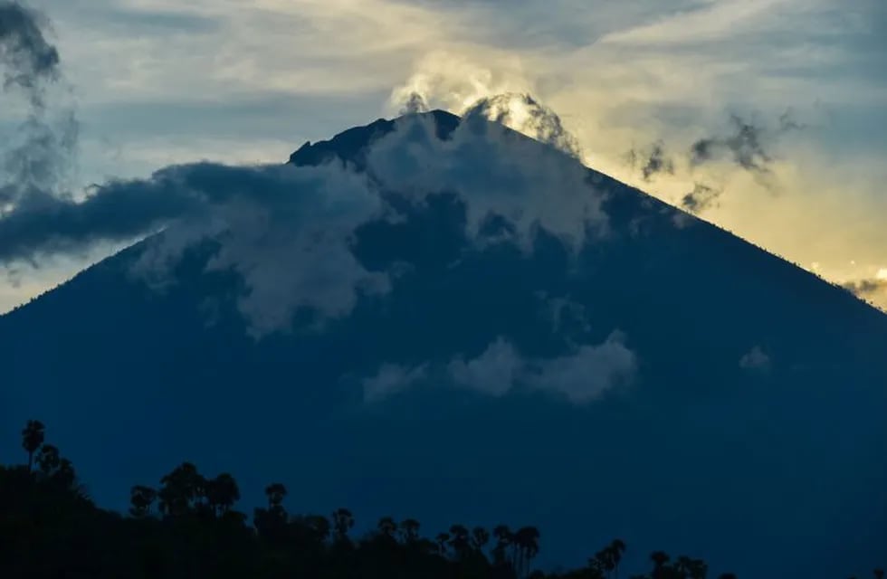 Mount Agung is during sunset in Amed beach, in Karangasem, on Bali island on September 29, 2017.\nA rumbling volcano on the holiday island of Bali is spewing steam and sulphurous fumes with more intensity, heightening fears of an eruption as officials said the number of evacuees had topped 144,000. / AFP PHOTO / BAY ISMOYO