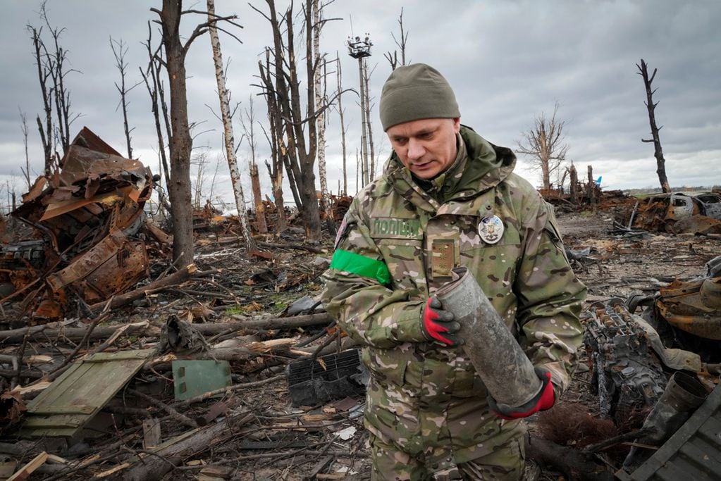 Un militar del Ministerio del Interior recoge proyectiles sin explotar, granadas, minas, después de las recientes batallas en Hostomel cerca de Kiev. (AP/Efrem Lukatsky)