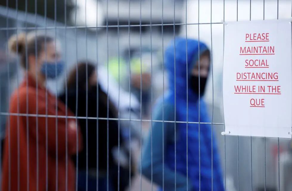 A sign hangs on a fence as people queue outside a test centre, following an outbreak of the coronavirus disease (COVID-19), in Southend-on-sea, Britain September 17, 2020. REUTERS/John Sibley