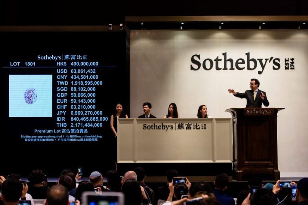 David Bennett (R), head of Sotheby's International Jewellery Division, prepares to hit the hammer to finalise the sale of a 59.60-carat giant diamond named the "Pink Star", breaking the world record for a gemstone sold at auction, fetching 71.2 million US