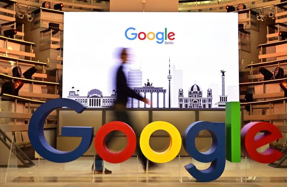 (FILES) In this file photo taken on January 22, 2019 a technician passes by a logo of US internet search giant Google during the opening day of a new Berlin office of Google in Berlin. - Google will pay partnered media publishers in three countries and offer some users free access to paywalled news sites, the tech giant said June 25, 2020. The announcement comes after legal battles in France and Australia over Google's refusal to pay news organizations for content.In a blog post the firm said they would launch \