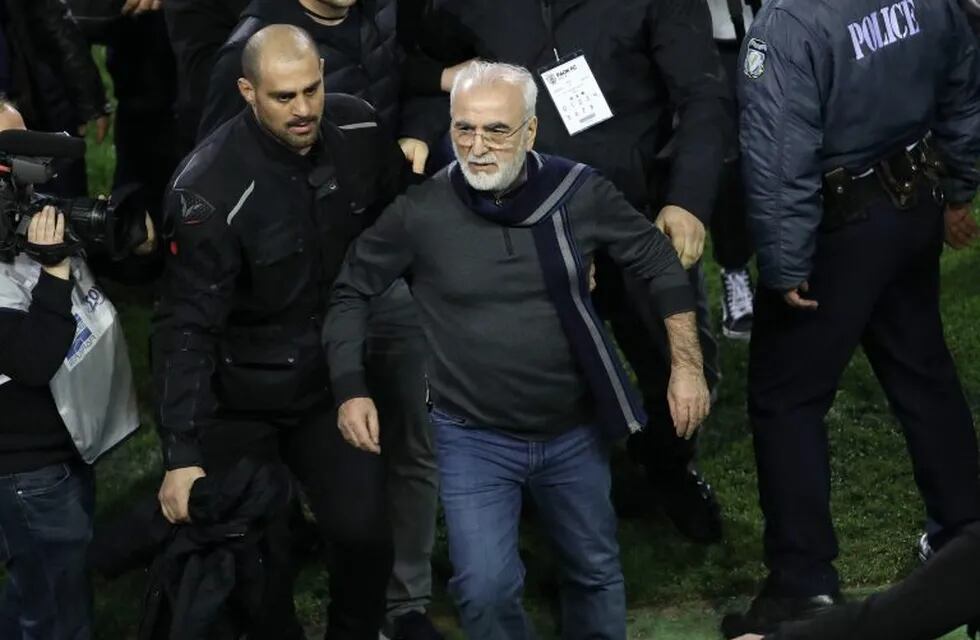 El presidente y propietario del PAOK griego, Ivan Savvidis , abandona el terreno de juego escoltado por sus guardaespaldas, tras invadir el campo con una pistola, durante el encuentro entre el PAOK Salónica y el AEK Atenas.