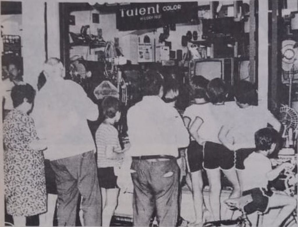 La gente se agolpa en las vidrieras de los negocios céntricos para apreciar las transmisiones de prueba de canal 2 (foto La Voz del Pueblo)