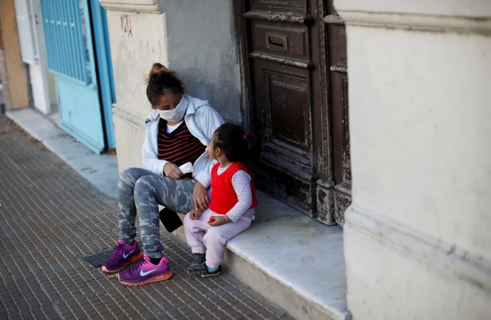 A woman and child sit on a door stoop in Buenos Aires, Argentina, Saturday, May 16, 2020. Children in the Argentine capital are now allowed limited outdoor recreation time on weekends for the first time since quarantine measures to help curb the spread of COVID-19 were put in place almost 2 months ago. (AP Photo/Natacha Pisarenko)