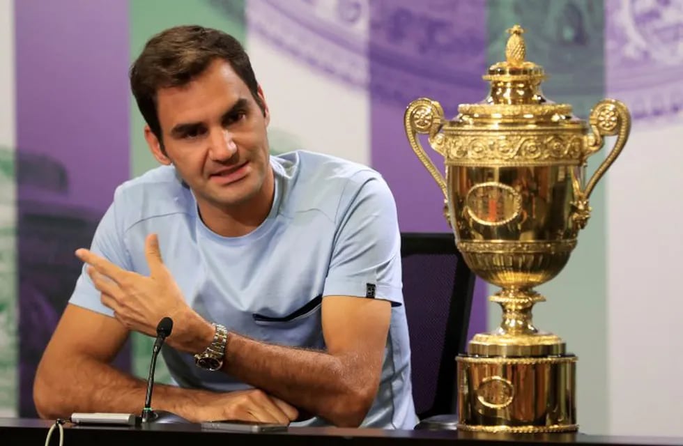 Switzerland's Roger Federer speaks next to the Men's Single's tennis trophy he won on Sunday during a photo call at The All England Lawn Tennis and Croquet Club, Wimbledon, England, Monday July 17, 2017. Federer's eighth Wimbledon title pushed him back up to No.3 in the ATP rankings. (Adam Davy/PA via AP)