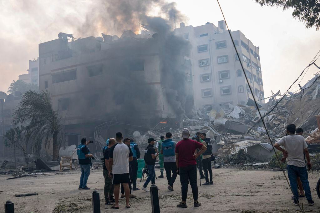 En esta imagen de archivo, reporteros observan mientras palestinos inspeccionan un edificio alcanzado por un bombardeo israelí en la Ciudad de Gaza, 8 de octubre de 2023. El limitado número de periodistas que están en Gaza tratan de informar sobre la guerra con Israel mientras sufren los mismos problemas que la asediada población palestina de la Franja.