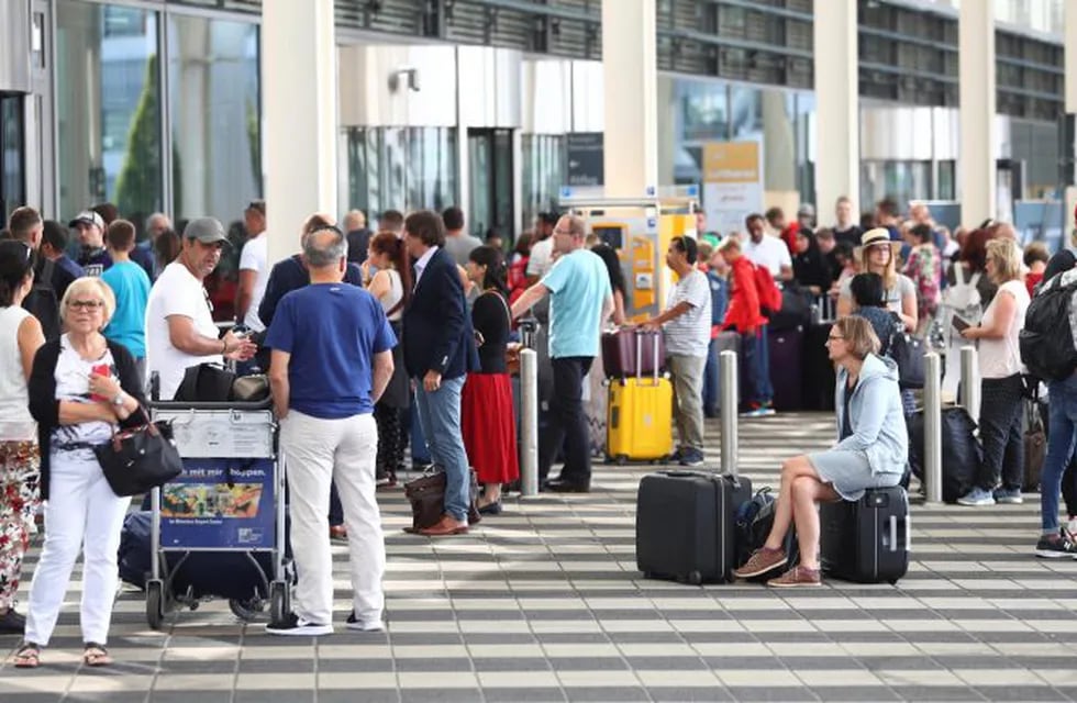People wait outside the Munich Airport in Munich, Germany, Tuesday, Aug. 27, 2019. Munich Airport says it has closed some of its terminals because a person has likely entered the \