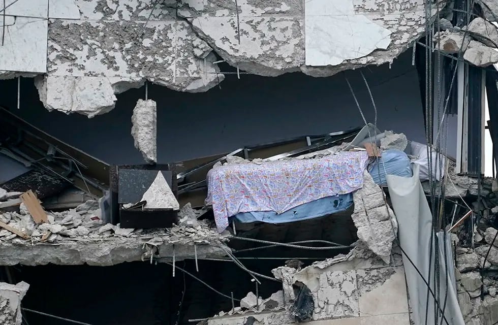 Una cama cuelga del edificio parcialmente destruido. (Foto: The Associated Press)