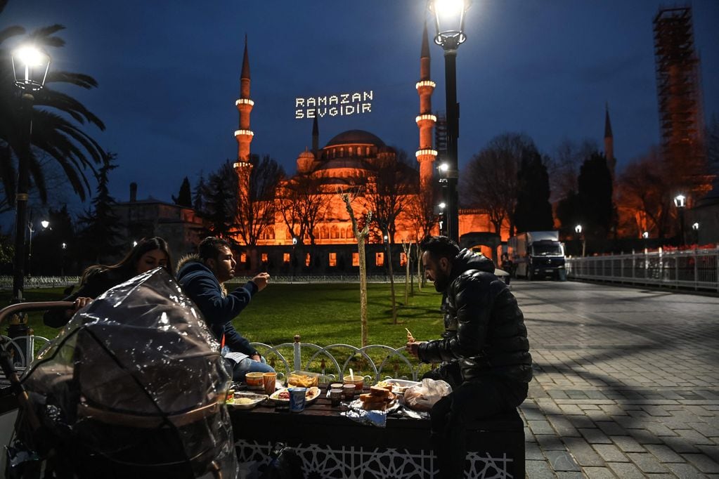 Un grupo comiendo el iftar luego del día de ayuno. De fondo, la mezquita Sultanahmet , conocida como "Mezquita Azul", que se ubica en Estambul, Turquía.