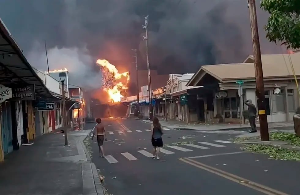 Varias personas observan mientras el humo y las llamas de los incendios forestales llegan a Front Street, en el centro de Lahaina, en Maui, Hawai, el 8 de agosto de 2023.
