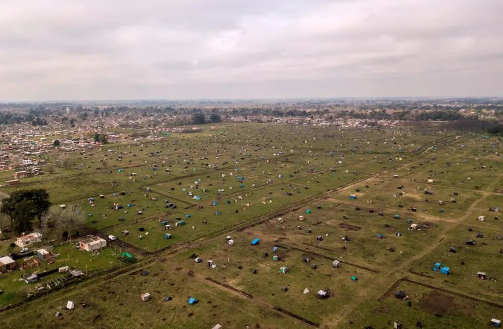 TOPSHOT - Aerial view showing tents and improvised shelters set up by homeless people in vacant land outside Guernica, in the province of Buenos Aires, south of the Argentine capital, on August 28, 2020 amid rising poverty in an economic crisis exacerbated by the COVID-19 novel coronavirus pandemic. - Outdoors or under makeshift tents, about 2,500 people have been defying justice, and COVID-19, for more than a month, when they occupied empty lots in Buenos Aires Province, the most populous of the country and where the pandemic is hitting the hardest. Scattered in over 100 hectares of vacant land, children run around and adults talk, while the police guards the area. Prevention measures against the novel coronavirus barely exist here. (Photo by Ronaldo SCHEMIDT / AFP)