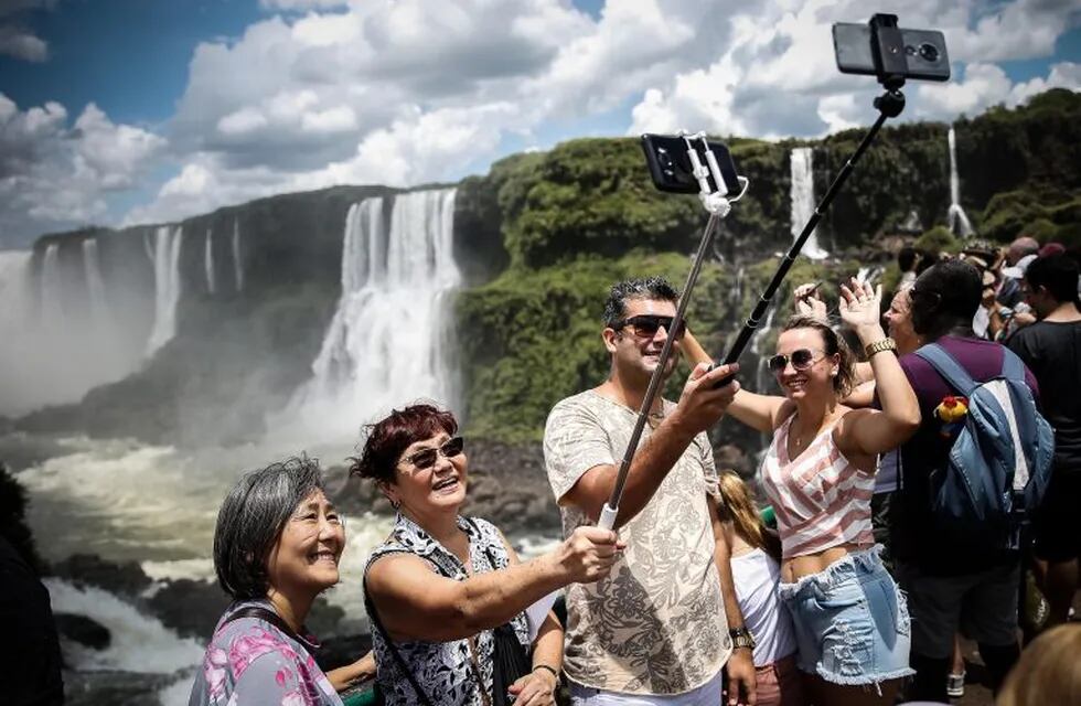 Turistas toman fotografías el 8 de febrero pasada con los saltos del Parque Nacional Iguazú como escenarios.  EFE/ Juan Ignacio Roncoroni