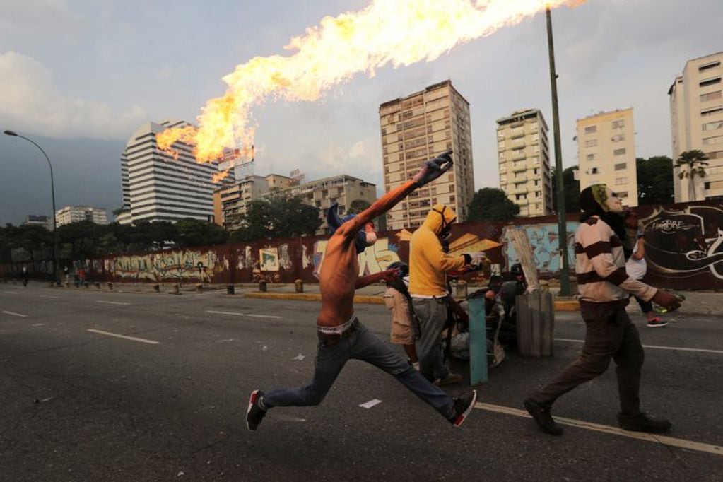 In this April 19, 2017 photo, an anti-government protesters throws a molotov bomb at security forces in Caracas, Venezuela. Tens of thousands of opponents of President Nicolas Maduro flooded the streets of Caracas in what's been dubbed the "mother of all 
