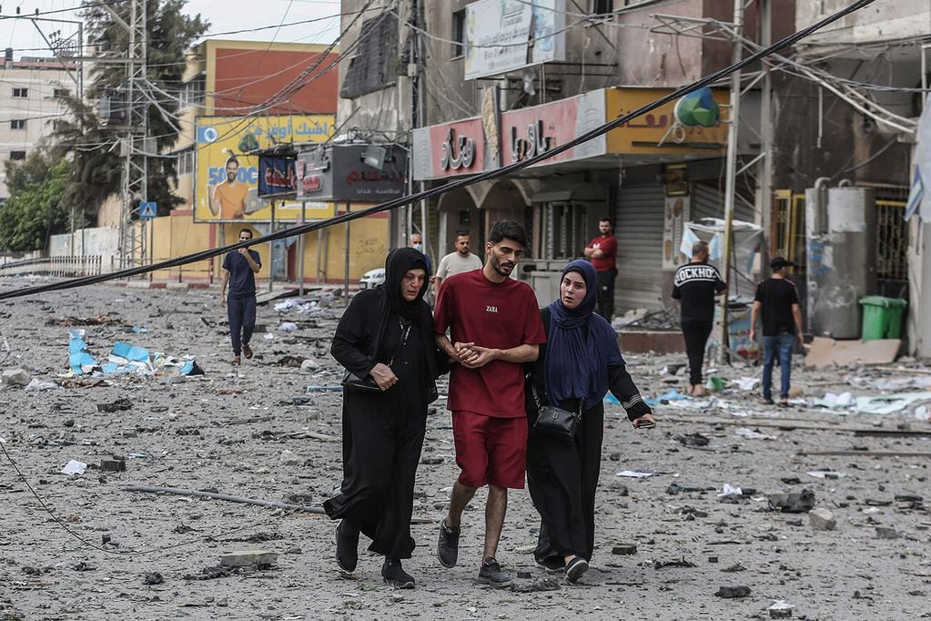 Palestinos caminan entre los escombros tras los ataques aéreos israelíes en el barrio de al-Rimal en la ciudad de Gaza. 