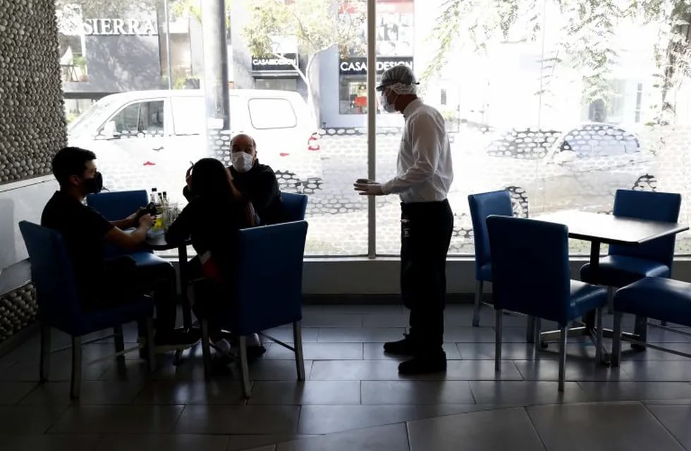 AME3636. LIMA (PERÚ), 21/07/2020.- Un mesero protegido con máscara atiende una mesa en el restaurante \