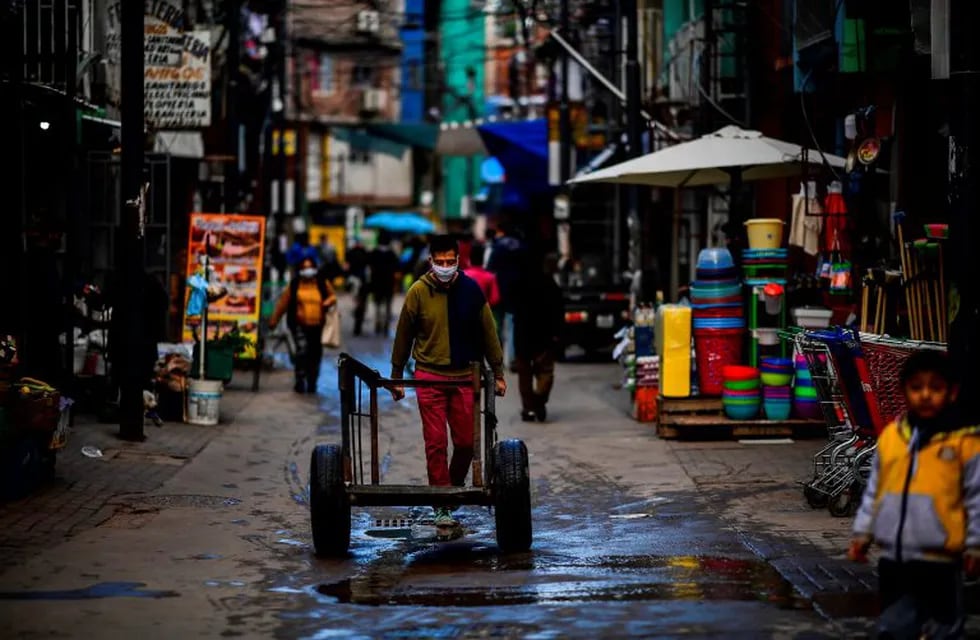 A man wearing a face mask as a preventive measure against the novel coronavirus, COVID-19, pushes a cart in Villa 31 shantytown in downtown Buenos Aires, on May 5, 2020. - Villa 31, the oldest shantytown in Buenos Aires, is separated only by an avenue from exclusive neighbourhoods of the capital. Crowded, hungry and suffering water services faults, residents of the slum now face the menace of COVID-19. (Photo by Ronaldo SCHEMIDT / AFP)