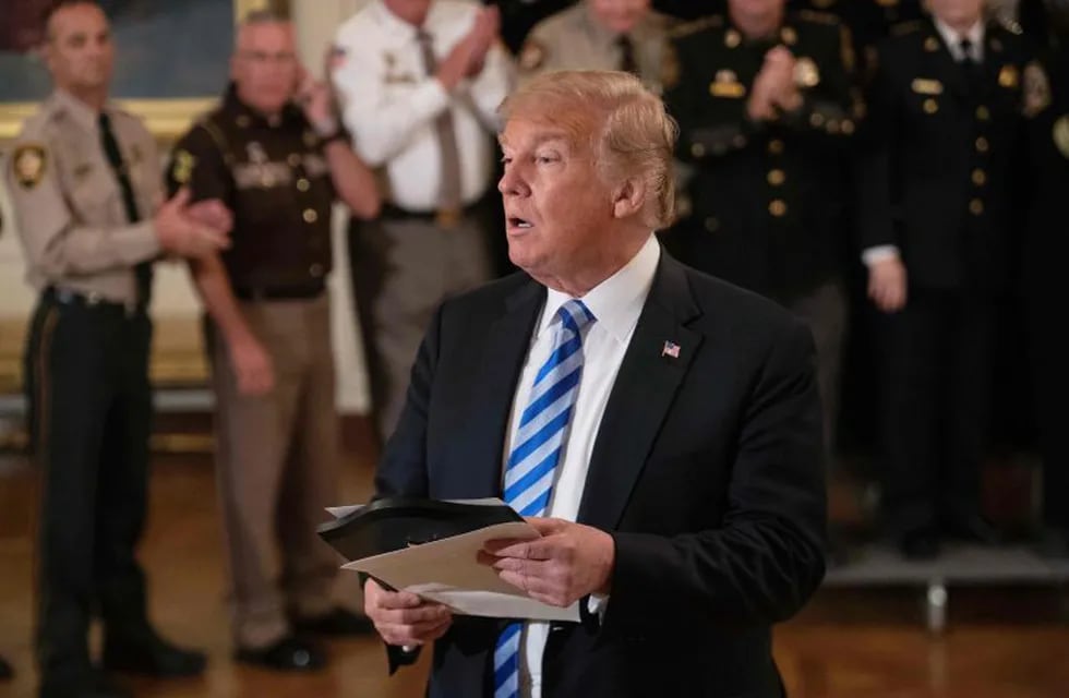 US President Donald Trump reads from an article praising his administration as he answers a journalist during a meeting with sheriffs at the White House in Washington, DC, on September 5, 2018. - Trump was responding to an anonymous \