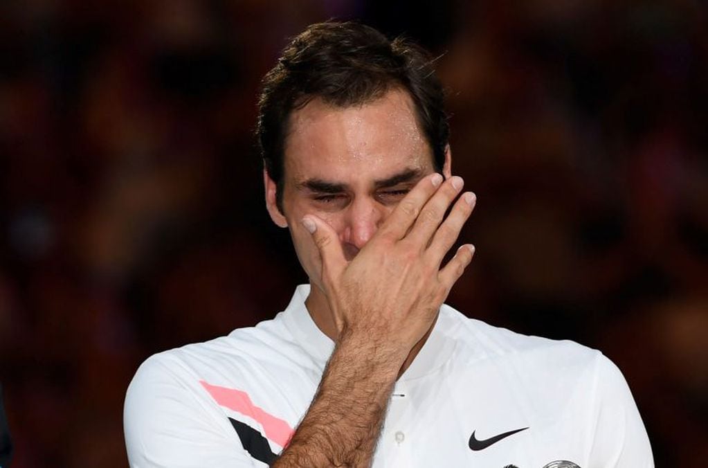 Switzerland's Roger Federer cries as he holds the winner's trophy after beating Croatia's Marin Cilic in their men's singles final match on day 14 of the Australian Open tennis tournament in Melbourne on January 28, 2018. / AFP PHOTO / SAEED KHAN / -- IMAGE RESTRICTED TO EDITORIAL USE - STRICTLY NO COMMERCIAL USE --