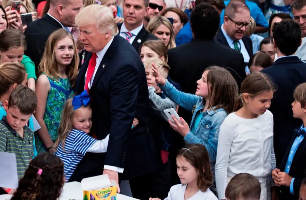 US President Donald Trump receives a hug during the Easter Egg Roll on the South Lawn of the White House April 17, 2017 in Washington, DC. / AFP PHOTO / Brendan Smialowski