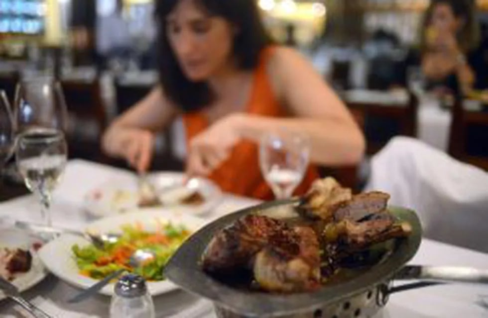 A woman eats meat at a traditional grill restaurant in Buenos Aires, on October 27, 2015. Sausages, ham and other processed meats cause bowel cancer, and red meat 