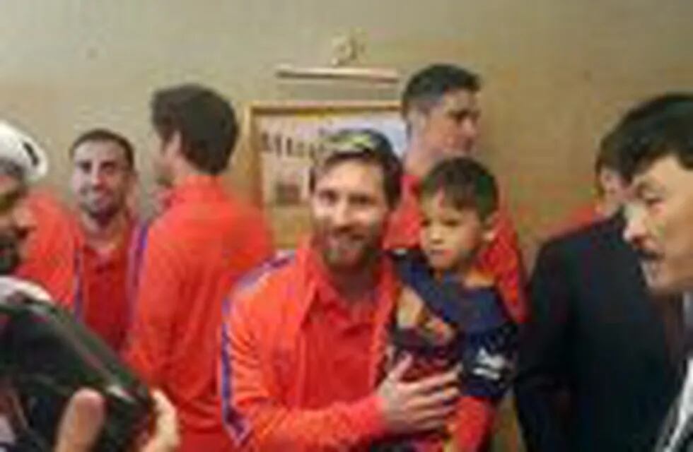 A handout picture released by Qataru2019s Supreme Committee for Delivery and Legacy on December 13, 2016 shows Barcelona's Argentinian forward Lionel Messi (C-L) holding six-year-old Afghan boy Murtaza Ahmadi (C-R) in Doha, upon the team's arrival to play a f