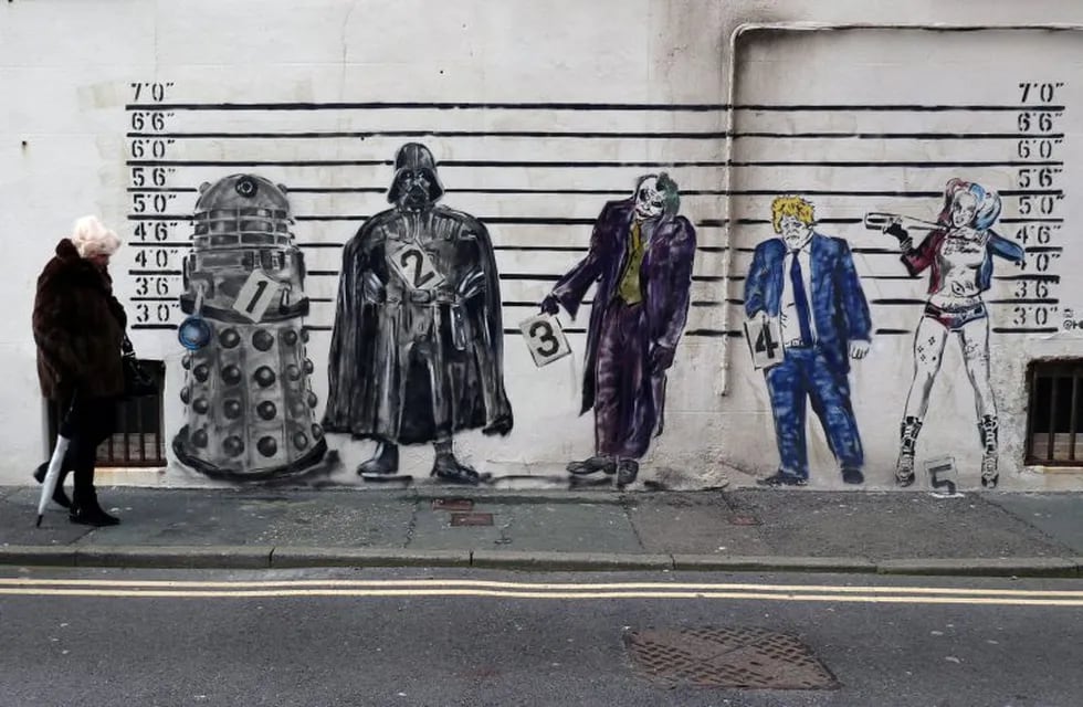 A woman walks past a graffiti mural that depicts Britain's Prime Minister Boris Johnson alongside fictional characters of a Dalek, Darth Vader, The Joker and Harley Quinn set against a line-up in Worthing, Britain January 25, 2020. REUTERS/Russell Boyce